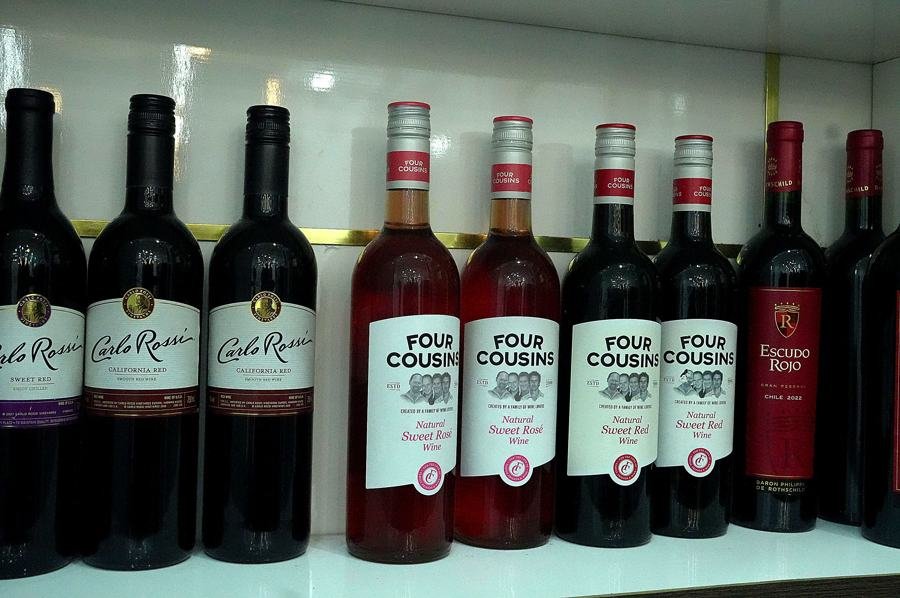 Shelf lineup of wine bottles: Carlo Rossi, Four Cousins sweet rose, Escudo Rojo