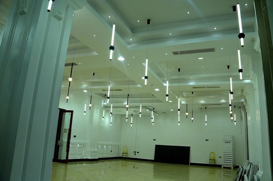 Same empty white hall from another angle showing far wall and doorways, tube pendant lighting